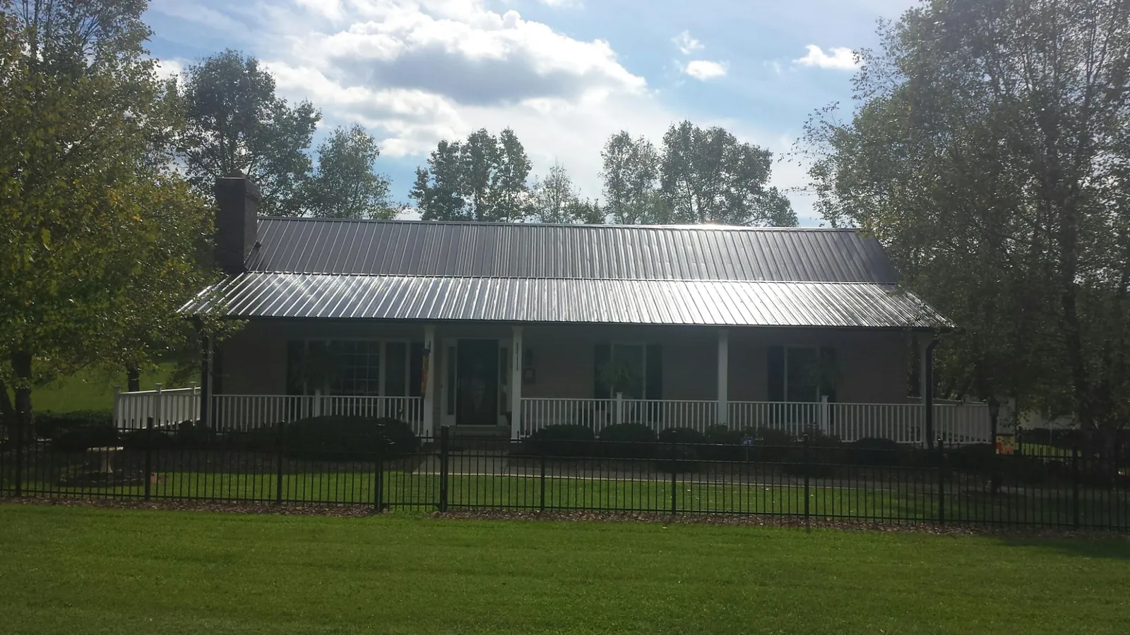 Gray metal roof on a brick ranch with a full width front porch — Gutter Guard Installation work by our crew in Milford