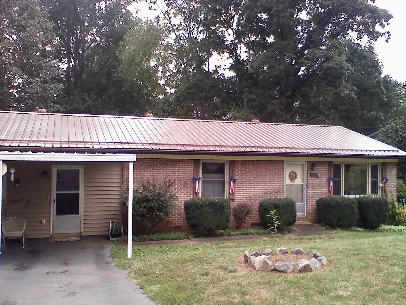 Bronze metal roof and carport on a brick ranch home — Roof Repair work by our crew in Milford