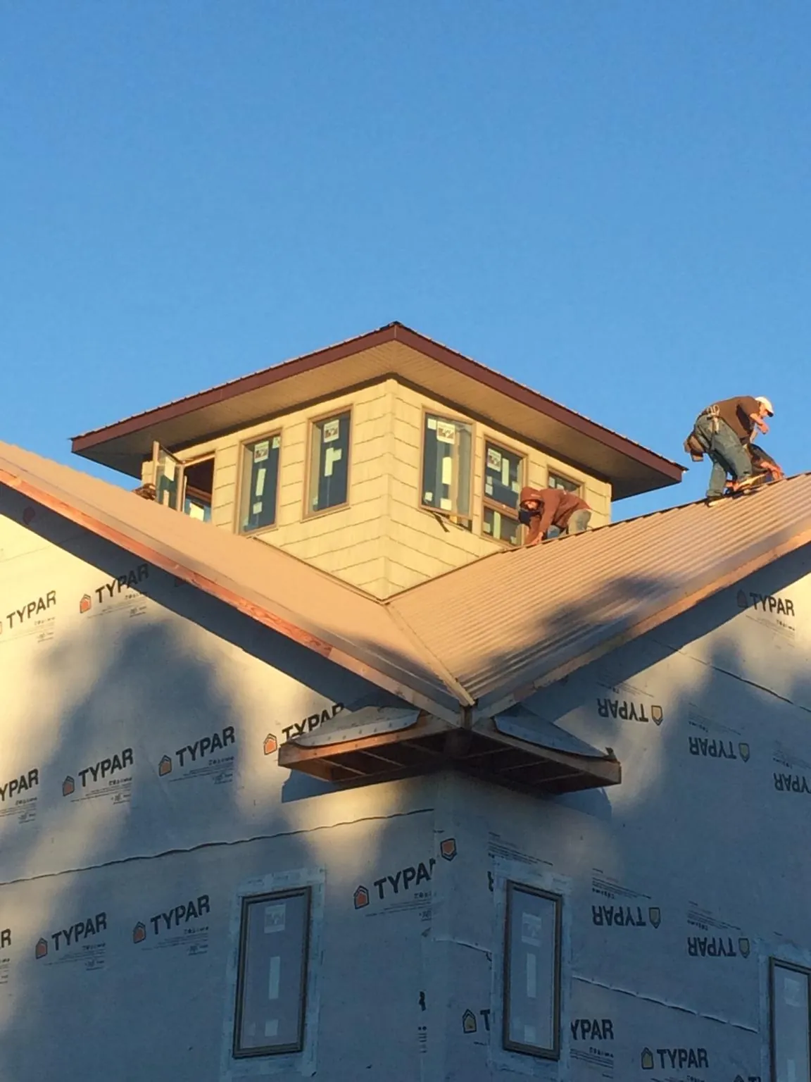 Roofers working around a rooftop cupola on a new metal roof at sunset — Roof Waterproofing in Milford by Roofing Brothers